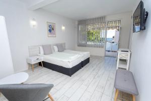 a bedroom with a bed and a tv and a chair at Guest rooms and apartments Desi in Balchik