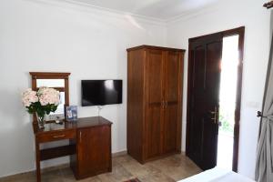 a bedroom with a television and a dresser with a cabinet at Cunda Deniz Hotel in Ayvalık