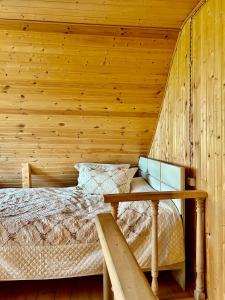 1 dormitorio con 1 cama y pared de madera en Cottage Racha Rhymes, en Ambrolauri