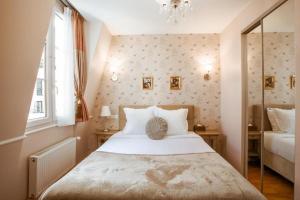 - une chambre avec un grand lit blanc et une fenêtre dans l'établissement La Maison Gobert Paris Hotel Particulier, à Paris