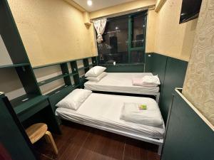2 camas en una habitación pequeña con ventana en 3D Inn Hong Kong - Dragon, en Hong Kong