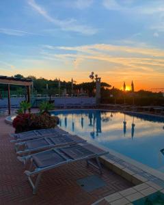 una piscina con due panchine di fronte a un tramonto di Resort Villa Flavio a Ischia
