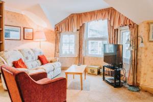 Welbeck Hotel & Apartments في دوغلاس: غرفة معيشة مع أريكة وتلفزيون