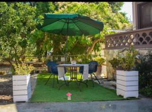 a table and chairs under an umbrella in a yard at Garden Rooms in Matala