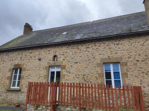 a brick house with a wooden fence in front of it at Gîte à la ferme Les Berges Rient in Chailland