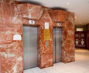 Tres ascensores están alineados contra una pared de ladrillo. en Antigoni Hotel, en Protaras