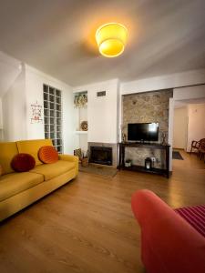 sala de estar con sofá amarillo y TV en Casa da Fonte Grande, en Belmonte