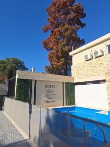a building with a swimming pool next to a tree at Hotel Mon Chéri in Villa Carlos Paz