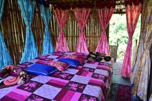 a bed in a room with pink and blue curtains at Harakoppa Hills in Padakalu
