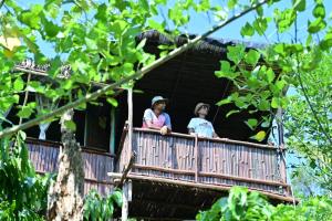 zwei Frauen auf einem Balkon eines Baumhauses in der Unterkunft Harakoppa Hills in Padakalu