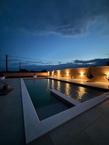 a swimming pool lit up at night with lights at Apartman Chiara in Galovac
