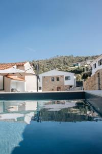 a swimming pool with blue water and buildings in the background at Casa Gondiga in Roriz