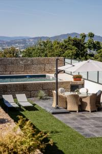 eine Terrasse mit Stühlen und einem Sonnenschirm neben einem Pool in der Unterkunft Casa Gondiga in Roriz