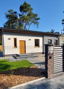 um edifício branco com uma cerca em frente em KOLUMNA HOUSE domek noclegowy z prywatną sauną I balią em Lask