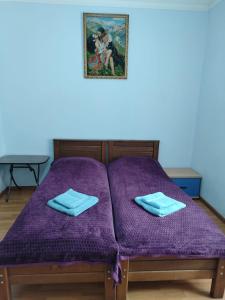 uma cama com lençóis roxos e uma foto na parede em Gia Home em Kobuleti