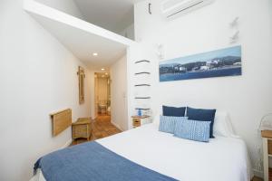a bedroom with a white bed with blue pillows at L'Hostalet de Cadaques in Cadaqués