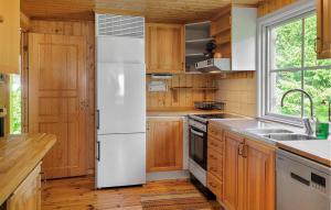 a white refrigerator in a kitchen with wooden cabinets at 2 Bedroom Amazing Home In Högsby in Högsby
