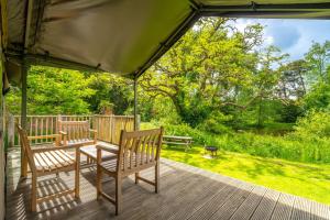 a porch with two wooden chairs and an umbrella at Osprey - Exton Park in Exton +19 photos