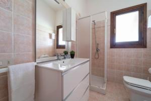 Un baño blanco con lavabo e inodoro. en Giardino con Vista Mare, en Codaruina
