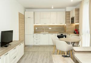 a kitchen with white cabinets and a table and a tv at Azur Delux -1BD Flat with Parking & Pool by Flat Mаnаger in St. St. Constantine and Helena