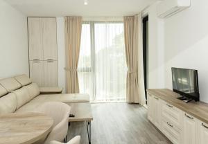 a living room with a couch and a television at Azur Delux -1BD Flat with Parking & Pool by Flat Mаnаger in St. St. Constantine and Helena