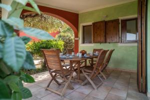 una mesa de madera y sillas en un patio con un arco en Giardino con Vista Mare, en Codaruina 23 fotos más