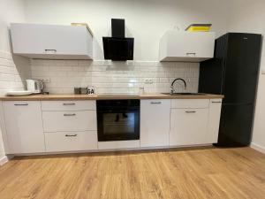a kitchen with white cabinets and a black refrigerator at Apartamenty Lipowy Zakątek in Iława