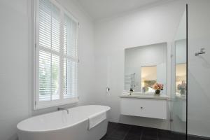 Un baño blanco con bañera y ventana. en The Cottage at Bolobek, en Macedon 11 fotos más