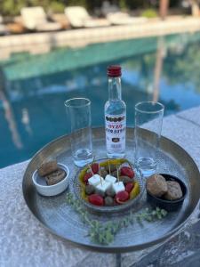 a plate of food with a bottle and glasses on a table at Aithonas Villa in Archangelos