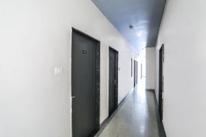 un pasillo con puertas negras y paredes blancas en FabHotel Convivial Sky en Raipur