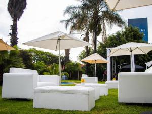 a group of white couches and umbrellas on the grass at Monte La Vue Hotel in Sandton