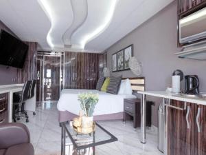 a bedroom with a bed and a desk and a kitchen at Monte La Vue Hotel in Sandton