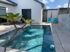 una piscina con una palmera en un patio trasero en Ô Ti' Lodge Vanilla en Bras-Panon