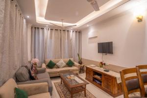 een woonkamer met een bank en een tv bij Hostie TJH - Cute Mini 2BHK apt, Saket, near Max Hospital in New Delhi