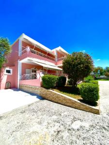 a pink house with bushes in front of it at Villa Marianna in Parga