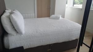 a bed with white sheets and pillows in a room at Stunning 1 Bed Studio Flat With FREE PARKING and FREE WIFI in Capella Court Purley in Purley