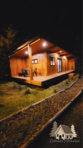 Cabaña de madera pequeña con porche por la noche en Cabañas Pulmahue en Colón