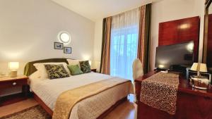 a bedroom with a bed and a desk and a television at Avalena Rooms in Zadar +32 photos