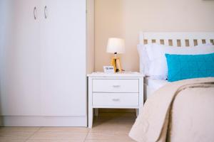 1 dormitorio con 1 cama con mesita de noche blanca y lámpara en Apartments Lungo Mare Ulcinj, en Ulcinj