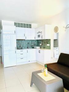 cocina blanca con sofá y mesa en Azahara Playa III, en Arona