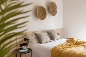 Líbere Barcelona Sant Antoni في برشلونة: غرفة نوم مع سرير مع الوسائد والقبعات على الحائط