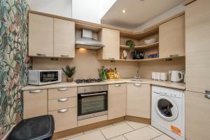 a kitchen with a washing machine and a microwave at Central Belfast Apartments Somerset Mews in Belfast