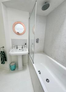 y baño blanco con lavabo y bañera. en Cockleshell Cottage en Falmouth