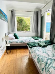 2 camas en una habitación con ventana en Cockleshell Cottage en Falmouth