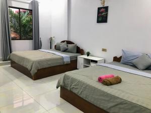 a bedroom with two beds with a stuffed animal on it at Orchid 101 in Kampot