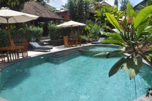 a swimming pool with chairs and umbrellas in a yard at Argasoka Bungalows in Ubud +57 photos