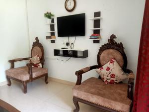 a living room with two chairs and a flat screen tv at Palolem garden estate in Canacona