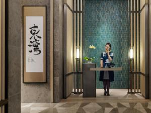 a woman is standing at a podium in a lobby at Mandarin Oriental, Shenzhen in Shenzhen