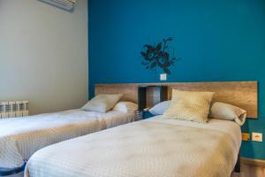 Hostal La Pastora في كانديليدا: سريرين في غرفة ذات جدار أزرق
