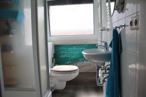 a bathroom with a toilet and a sink and a window at Ferienwohnung ELPIDA in Rodewisch